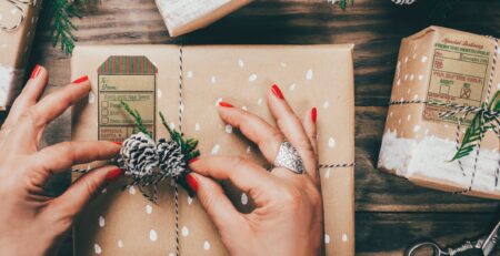 Holiday gift tag stickers on kraft-wrapped presents with twine and festive wreath decorations, featuring rustic North Pole and Santa delivery label designs.