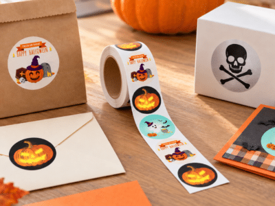 Halloween stickers on a roll alongside decorated treat bags, gift boxes, and paper crafts