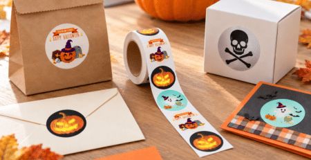 Halloween stickers on a roll alongside decorated treat bags, gift boxes, and paper crafts